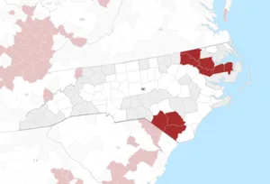 Map of North Carolina counties with two clusters, near the Northeast and the Southeast of the state, colored dark to indicate persistent poverty.