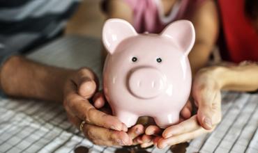 hands holding a pink piggy bank