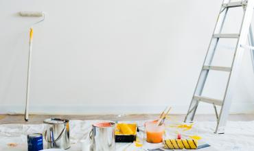 Blank wall with paint supplies on the ground and a ladder