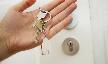 A hand holding keys in front of a door