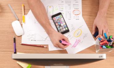 A hand on a table working on a mobile device