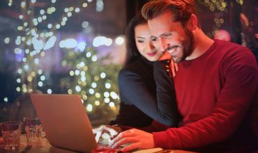 Couple looking at computer screen, with Christmas tree in background