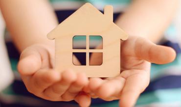 hands holding a wooden toy house 