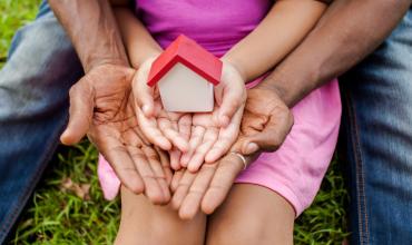 A man and a child holding a little house in their hands together