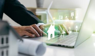 Severe Housing Affordability Challenges Worsen for Many North Carolinians A person sitting on this computer with fictional houses coming out of the computer