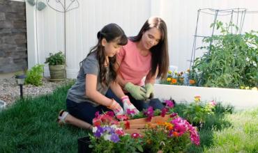 Mom and daughter planting flowers in their yard