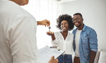 What Home Buyers Should Know About Escrow Two people accepting a key for their home from a real estate agent
