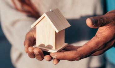 A person holding a small model of a home in their hands