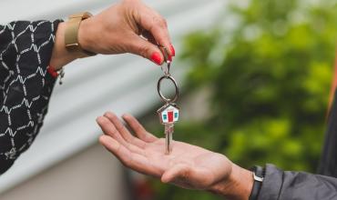 A hand placing a key in another person's hand