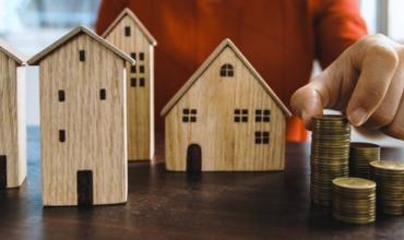 Array of small wooden houses on a table with coins