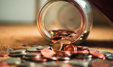 coins falling out of a glass jar onto a table