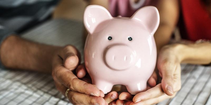 hands holding a pink piggy bank