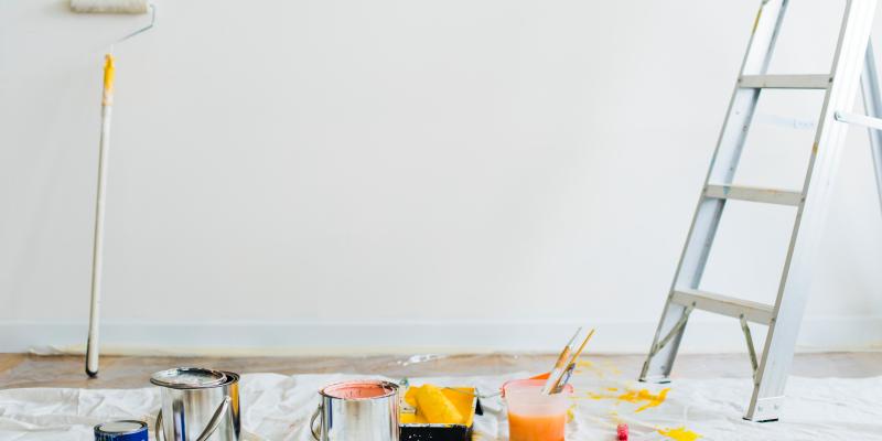 Blank wall with paint supplies on the ground and a ladder