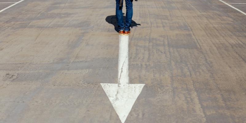 A person standing on an arrow in the road