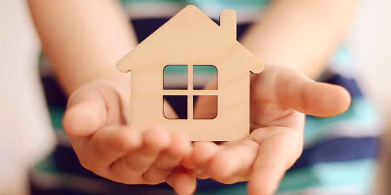 hands holding wooden house