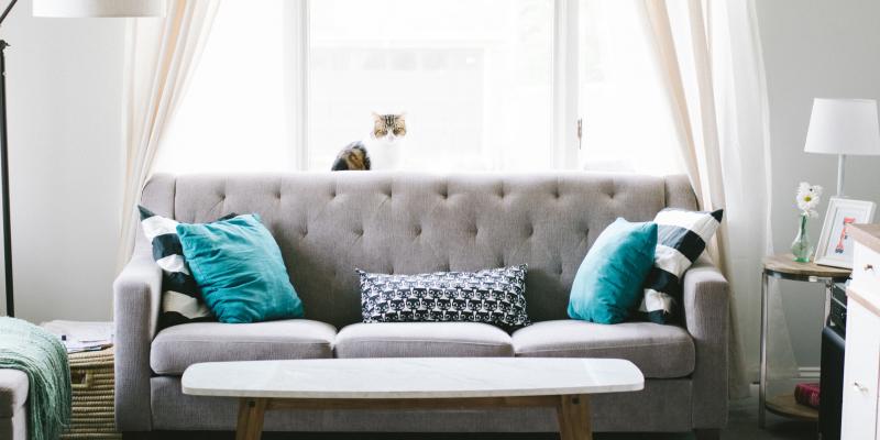 A gray couch with blue pillows and a coffee table in front of it