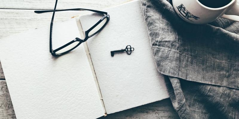 glasses sitting on top of a notebook with a key