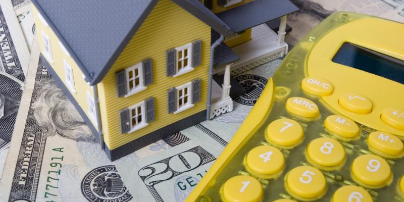 A toy house and a yellow calculator on a table