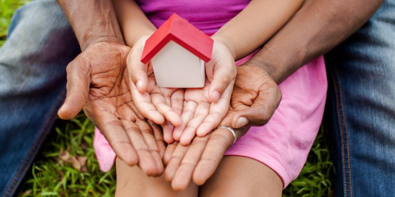 A man and a child holding a little house in their hands together