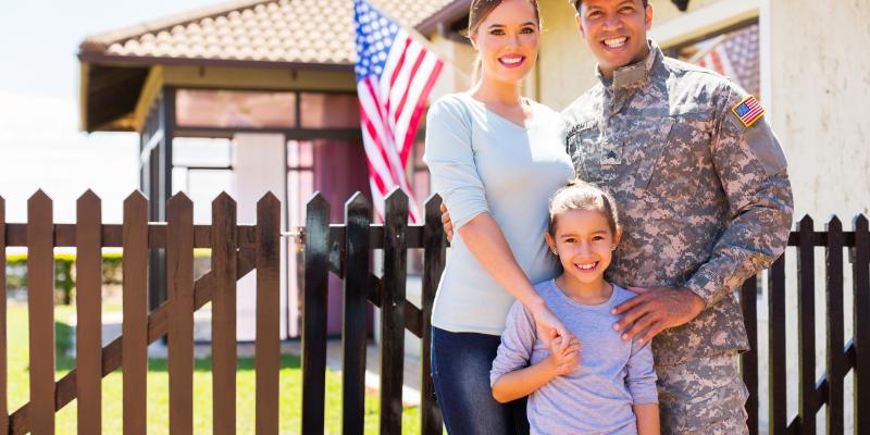 A military family standing in front of their home