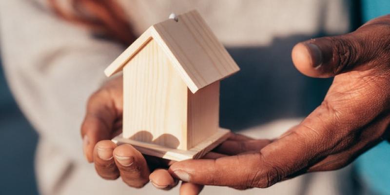 A person holding a small model of a home in their hands