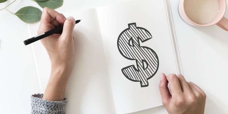 A dollar sign written in a notepad on a desk