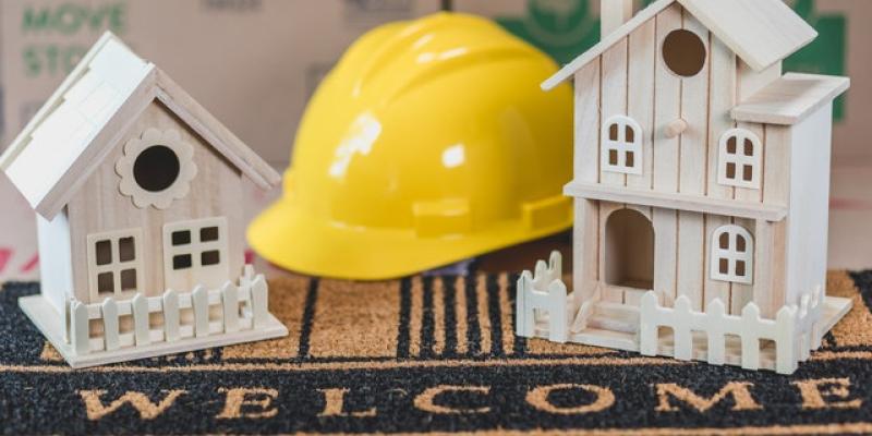 Two little houses with a hard hat on top of a welcome mat