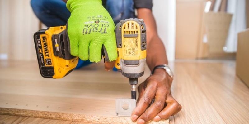 Guy drilling a hole into hardwood floor